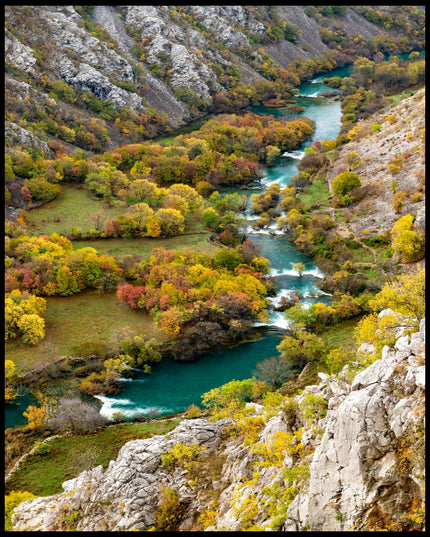 Leinwandbild von einem Fluss der sich, umgeben von mehreren Büschen, durch eine Berglandschaft erstreckt.