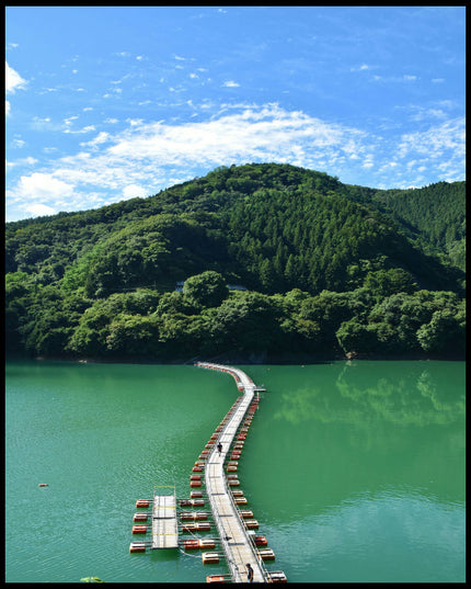 Leinwandbild von einer schwimmenden Brücke auf einem grünlichen See, die in einen Wald hinein führt.