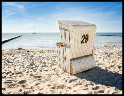 Leinwandbild von einem weißen Strandkorb am Strand der in Richtung Meer gerichtet ist.