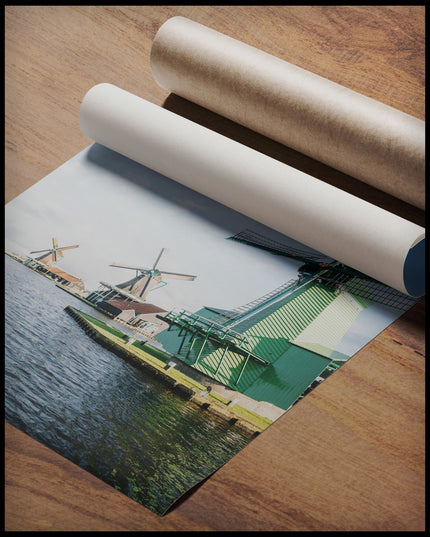 Ein Poster von drei Windmühlen aus Holz die am Wasser stehen, gerollt auf einer Holzoberfläche liegend